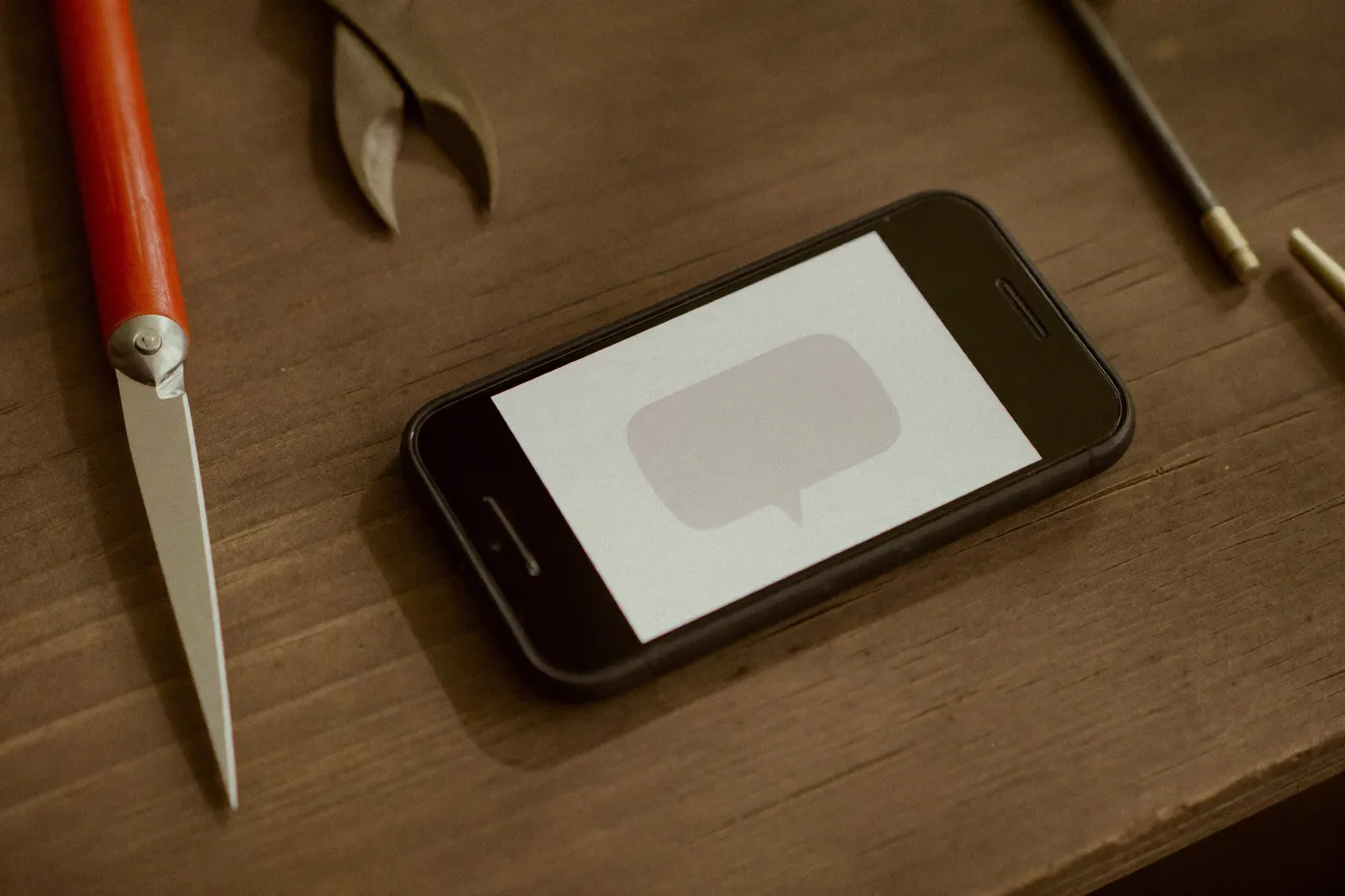 A smartphone on a workbench glowing with a new enquiry notification — an instant acknowledgement ready to send